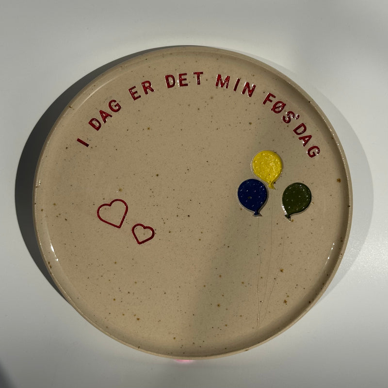 Fødselsdagstallerken i keramik med teksten I dag er det min føs'dag, to hjerter og tre balloner